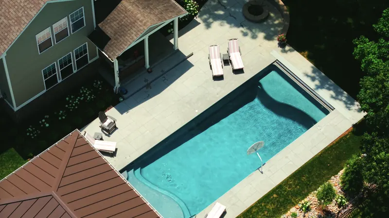 Aerial view of the pool deck, loungers and fire pit beside the home