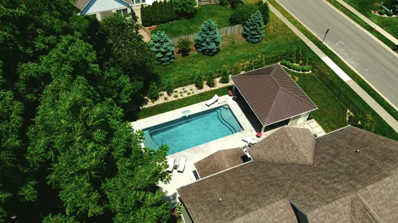Drone view of the backyard showing the pool, pool house and privacy plantings along the fence
